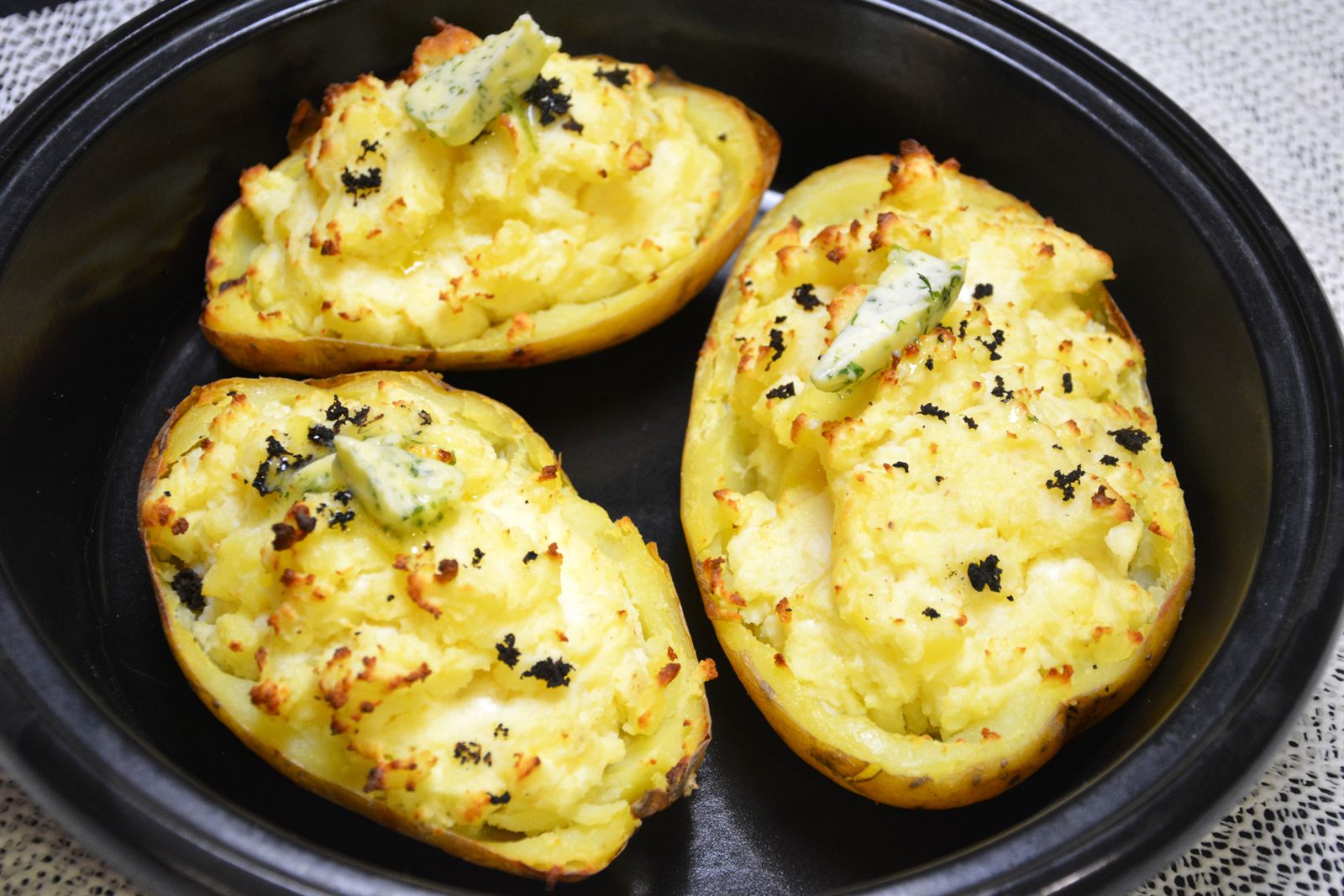 Gefüllte Ofenkartoffeln mit Feta und Kräuterbutter in einer schwarzen Auflaufform
