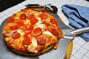 Deep Dish Pizza mit dickem Boden, geschmolzenem Mozzarella, Pepperoni und eingelegten Perlzwiebeln