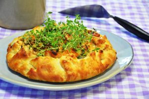 Galette mit Hähnchen, Bacon und Süßkartoffel mit eingeschlagenem Rand, frisch gebacken auf Backpapier