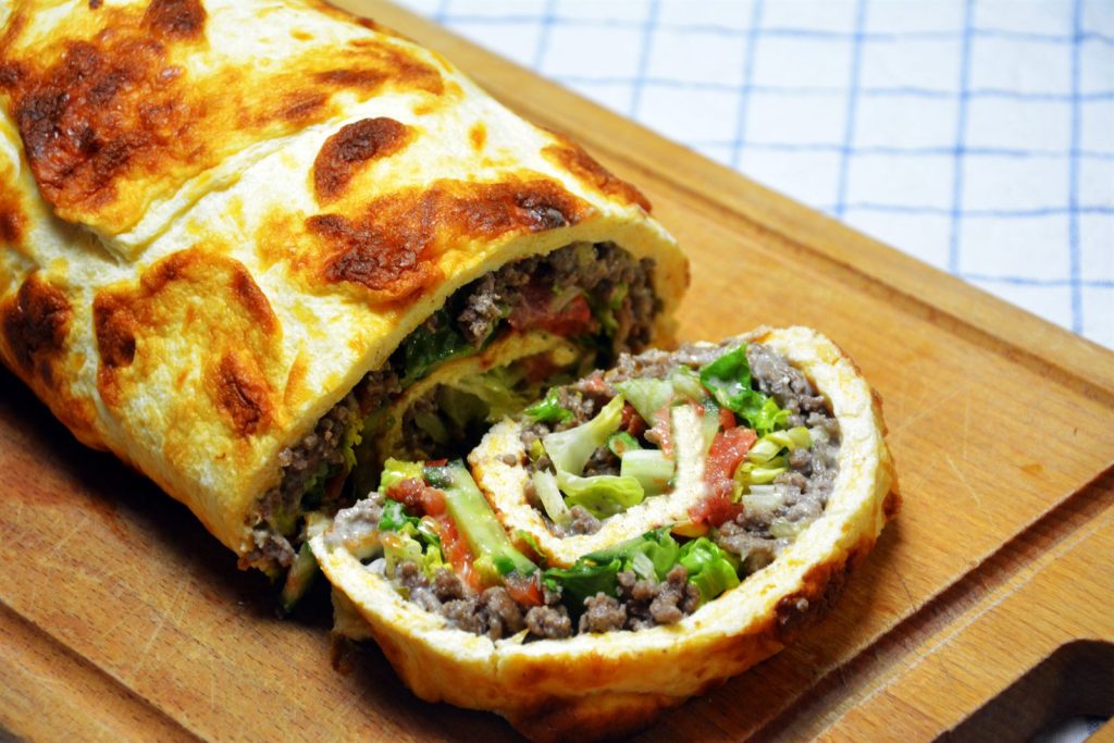 Low Carb Big Mac Rolle in Scheiben geschnitten mit Hackfleisch, Salat, Tomate, Bacon und Soße
