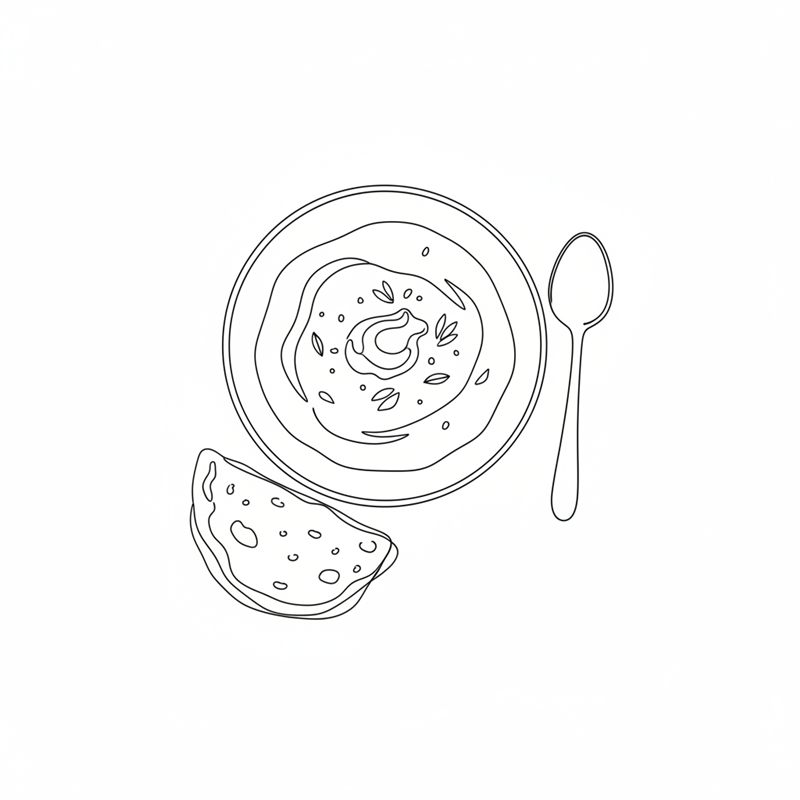 Eine Schüssel Kichererbsen-Curry, leicht von oben gesehen, mit einem Klecks Schmand und ein paar Blättern obenauf; ein Löffel und ein Stück Fladenbrot liegen daneben.